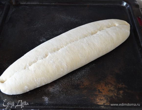 Тем временем, разогрейте духовку до 230°C вместе с подносом, на котором будете выпекать хлеб. Осторожно с полотенца переложите хлеб на горячий противень и поставьте в духовку. Сбрызните стенки духовки и сам хлеб из пульверизатора водой и закройте дверцу духовки.