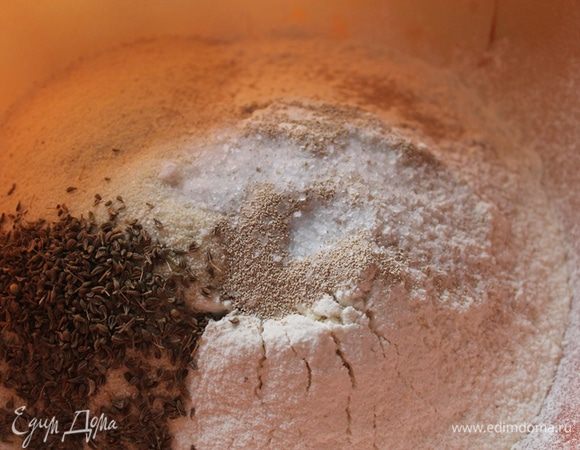 В чашку просеять муку, добавить манку, анис, дрожжи, соль. Вливаем воду и замешиваем тесто.