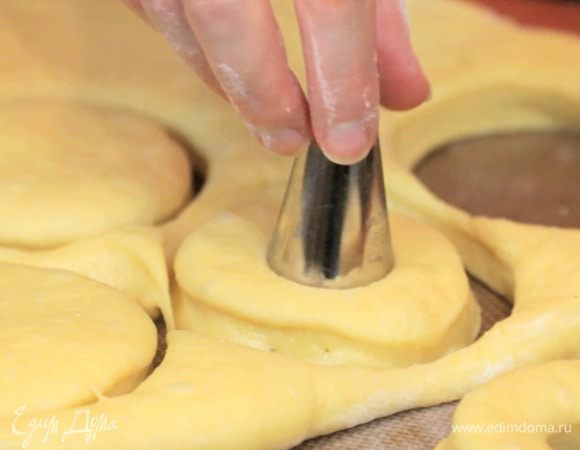 Раскатать тесто толщиной 1-1,5 см, вырезать круги диаметром 7-8 см и сделать отверстия в центре. Переложить на противень для запекания и оставить на 30 минут. Затем выпечь в духовке при 180°C 8-12 минут.