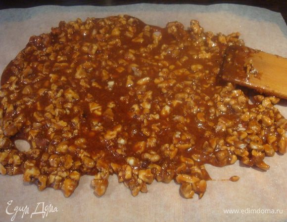 Бумагу для выпечки немного смазываем растительным маслом. Выкладываем орехи в карамели, разровняем на поверхности.