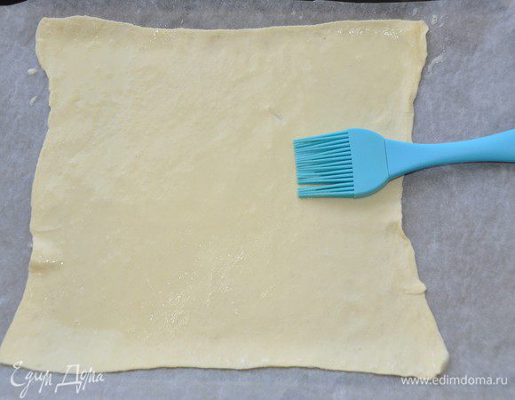 Стол чуть припылить мукой и раскатать тесто в прямоугольник толщиной около 3 мм. В этот раз у меня не большие пластины теста, поэтому противень я взяла небольшой 34х23 см.  
Желток взбить с водой и силиконовой кисточкой смазать тесто. 