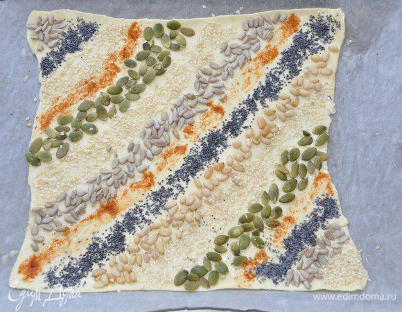 Попеременно выложить семена и семечки вдоль диагонали, чуть вдавливая их в тесто. 