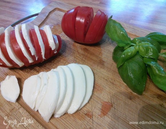 Помидоры (лучше крупная сливка) нарезать острым ножом ломтиками, но не до конца. Моцареллу нарезать тонкими слайсами. Мне хватило одного шарика моцареллы на две помидоры. Базилик помыть, обсушить, порвать на кусочки. Вложить в разрезы помидора ломтики моцареллы.
