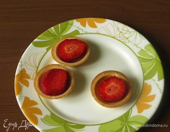 Разогреваем духовку. На тарталетки кладем клубнику.