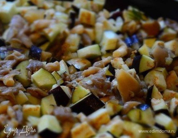 К содержимому добавить порезанные кубиками баклажаны. Перемешать и тушить еще 7 минут.