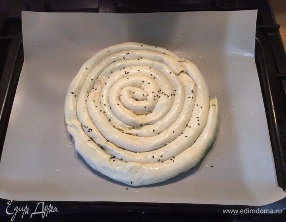 Чтобы пирог лучше подрумянился, нужно смазать его сладкой водичкой. Для этого размешиваем 1 чайную ложку сахара в 1/4 стакана воды. Для украшения сверху посыпаем спиральный пирог кунжутом. 