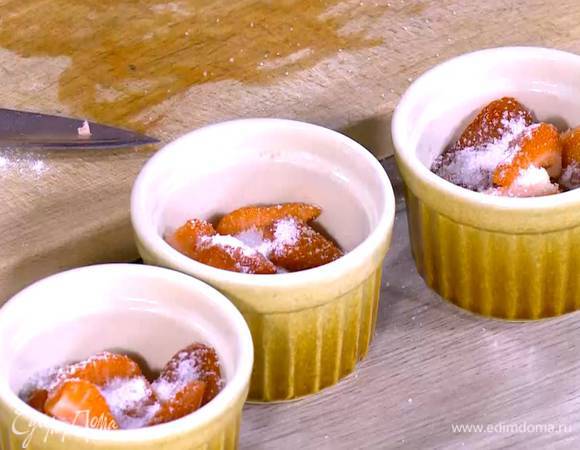 Клубнику разрезать на 4 части, выложить на дно небольших керамических форм и посыпать оставшимся сахаром и частью миндальных лепестков.