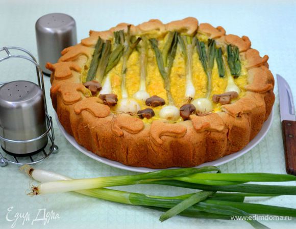 Поставить в заранее разогретую до 180°C духовку на 5 минут, чтобы яйца сверху немного схватились. Выложить молодой лук и грибы в произвольном порядке. Если головки лука большие, можно проварить их минуты 2, а потом выложить на пирог. Поставить в духовку еще минут на 30. Сверху сразу прикрыть фольгой.