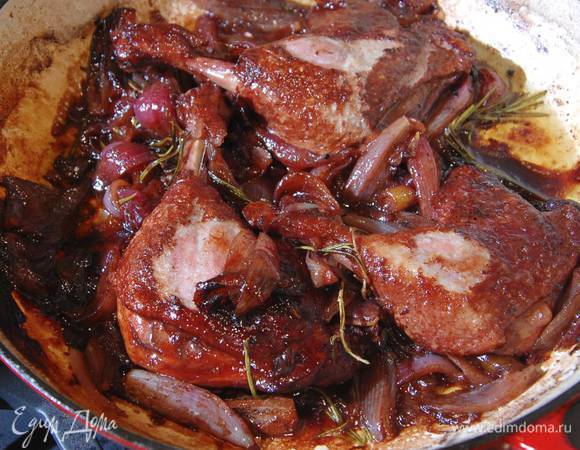 Влить бальзамический уксус, красное вино и довести до кипения, затем накрыть крышкой и тушить ножки еще около часа до готовности.