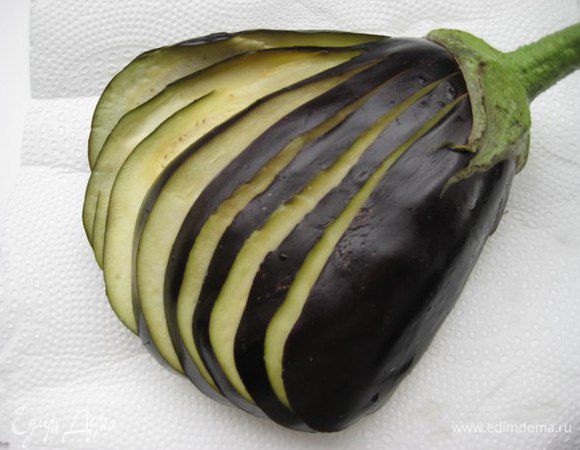 Баклажаны надрезать острым ножом вдоль, раскрыть как веер, посолить каждый слой. Через 10 минут промокнуть бумажными полотенцами выделившуюся влагу.