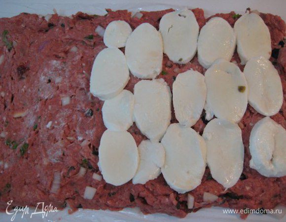 Выложить фарш на пищевую пленку, разровнять, сформировать прямоугольник. Моцареллу порезать дольками, выложить на фарш.
