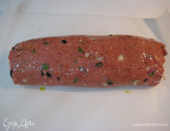 С помощью пленки свернуть фарш в рулет, смазать оливковым маслом. На противень положить бумагу для выпечки, выложить рулет по центру, завернуть рулет в бумагу как конфету. 