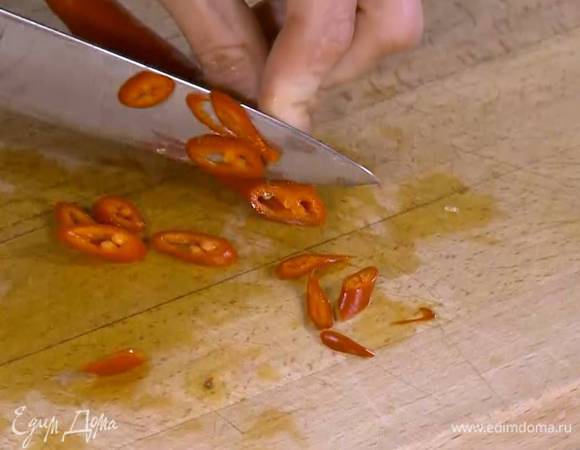 Перец чили, удалив семена, нарезать тонкими кольцами и добавить в сковороду.