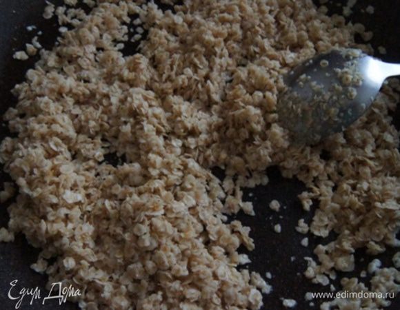 Овсяные хлопья обжарить на растительном масле (1 ложку оставить для смазывания бумаги) около 5 минут помешивая.