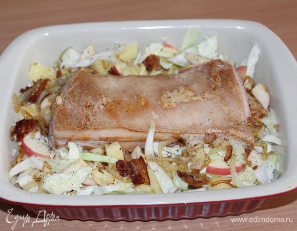 Капусту покрошить, яблоко порезать и выложить в форму. Сверху выложить мясо и обжаренный лук с беконом, дольки чеснока, посолить, поперчить по вкусу, добавить немного воды или овощного бульона (у меня была очень сочная капуста, жидкости понадобилось совсем немного). Закрыть форму фольгой или крышкой и отправить в духовку на час при 180-200°С.