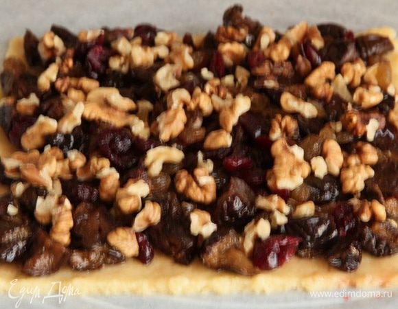 Раскатываем 2-й корж, смазываем его вареньем, выкладываем чернослив, сверху изюм и вишню, а потом орехи.