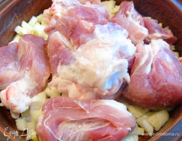 Лук очищаем и нарезаем кусочками. Половину лука укладываем в посуду в которой вы будете готовить, лучше керамическая или глиняная как у меня, сверху мясо.