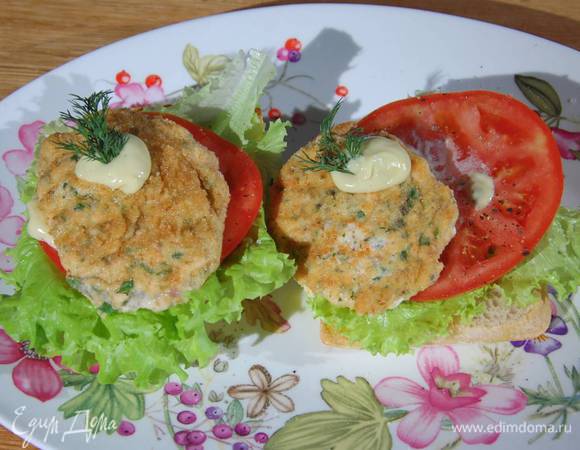 Обжаренный хлеб сбрызнуть оставшимся оливковым маслом, разложить на него листья салата, кружки помидора, посолить, поперчить, смазать домашним майонезом, сверху поместить рыбные котлетки, еще немного смазать майонезом и украсить оставшимися веточками укропа.