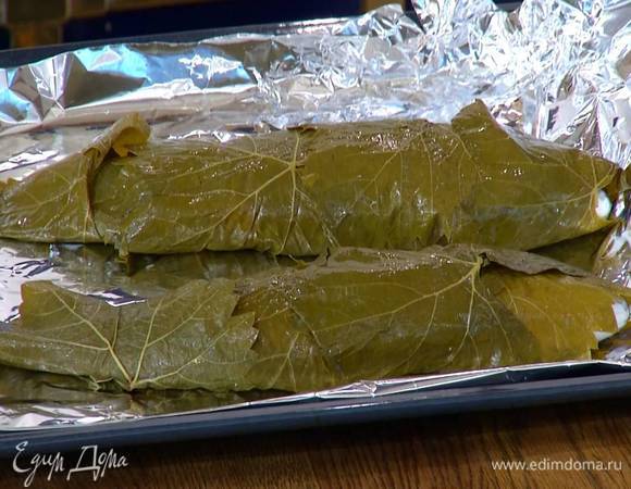 Обложить рыбу со всех сторон виноградными листьями и выложить на выстеленный пищевой фольгой противень.