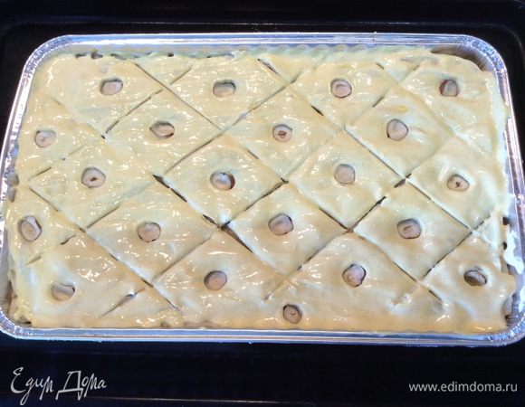 Расстилаем последний 7 толстый слой на поверхность и легким нажатием кончика ножа делаем набросок, чертя диагональные линии. Делим фундук пополам и втыкаем в центр каждого ромбика. Смешиваем сметану с куркумой и смазываем ею поверхность пахлавы.
