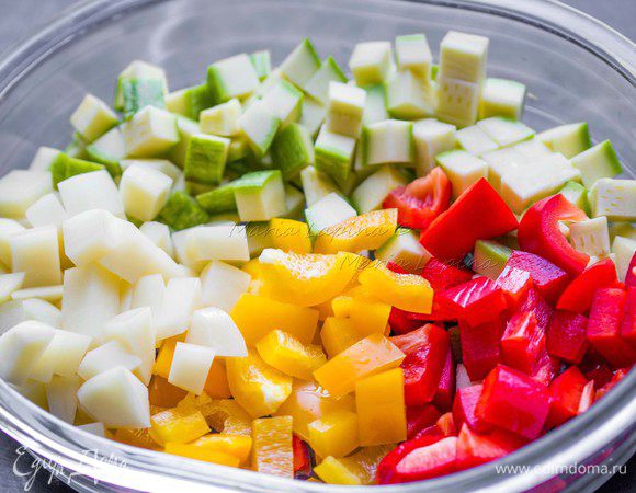 Остальные овощи: картофель, кабачок и перцы нарезаем кубиками чуть меньшего размера, чем баклажан. Баклажан промокнем бумажным полотенцем, снимаем с него влагу, а вместе с ней возможную горечь. Смешиваем все овощи и солим. Овощи нужно немножко не досолить, т. к. в блюде присутствует соленая фета.