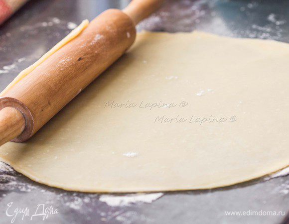 Раскатаем тесто с тонкий круглый пласт, перенесем на противень с пекарской бумагой.