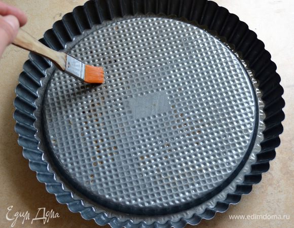 Для приготовления торта используем специальную форму для выпечки открытых пирогов (кростат) со слегка выдающимся центром. Используя обыкновенную форму для тортов (28 см), после приготовления бисквита необходимо аккуратно вырезать середину бисквита на глубину 1 см, отступив от края также 1 см. Вынуть часть мякиша. Итак, первым делом тщательно смазать форму растопленным сливочным маслом и отставить в сторону. Пока будем заниматься приготовлением теста, масло должно схватиться на поверхности формы тонкой пленочкой.