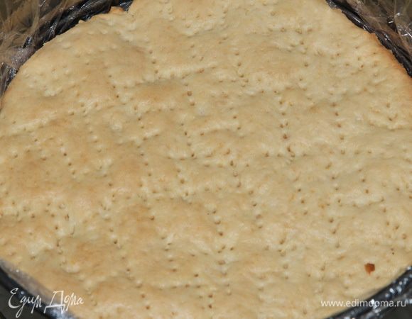 Форму выстилаем пищевой пленкой и начинаем в форме собирать пляцок. Поскольку я уменьшила и масло в рецепте, и творог взяла обезжиренный, я пропитала коржи, пока они были еще горячими — молоком. Хорошо пропитала. Кладем корж в форму.