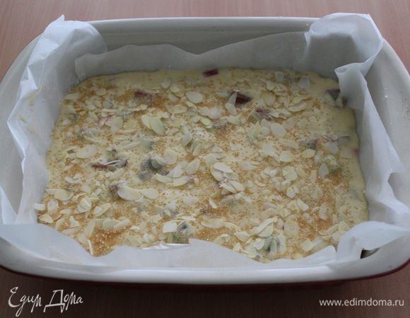 Переложить тесто в застеленную бумагой  форму и разровнять. Присыпать сверху миндальными лепестками и коричневым сахаром.