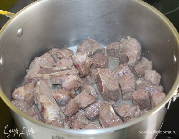 Мясо нарезать кубиками 3-4 см. В толстостенной кастрюле разогреть растительное масло и обжарить мясо со всех сторон до золотистой корочки.