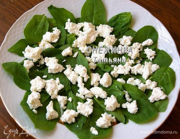 На блюдо выкладываем шпинат. Сыр разделываем на кусочки и раскладываем на зелень.