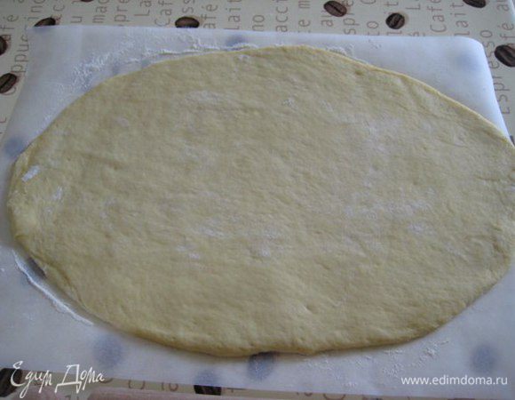 Готовое тесто обмять, выложить на бумагу для выпечки, присыпанную мукой. Раскатать тесто в овал.