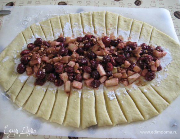 Центр теста присыпать крахмалом, выложить в центр начинку, сделать косые надрезы, сплести плетенку. Накрыть вторым листом бумаги для выпечки, дать подойти полчаса. Тем временем разогреть духовку до 180°C.