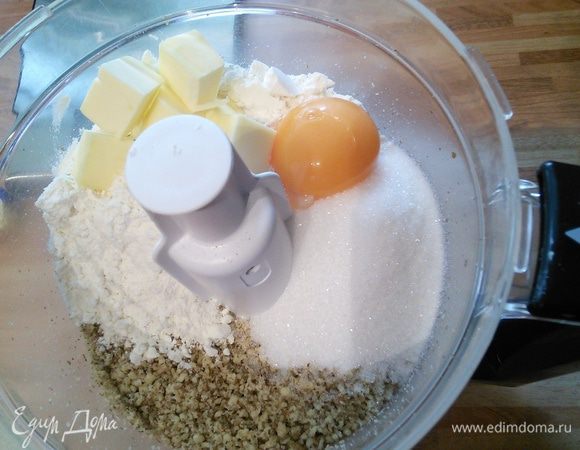 Добавьте в орехи муку, холодное масло, нарезанное на кусочки, сахар и ложку холодной воды. 