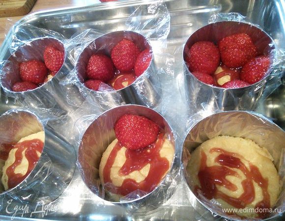 Смазать донышко пирожного клубничным вареньем и выложить половинки клубничек разрезом наружу, широкой стороной вниз. Мелкие целые ягоды кладем в середину. 