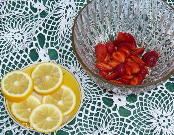 Нарезать клубнику. Сложить в крюшонницу. За ее неимением я воспользовалась двумя салатниками. Лимон нарезать кольцами и добавить к клубнике.