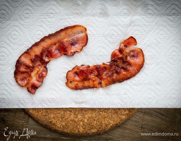 Поджарить до румяности ломтики бекона на сухой сковороде и выложить на бумажное полотенце, чтобы убрать лишний жир.