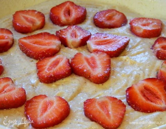 Форму смазать маслом (диаметр 20 см) и присыпать манкой или мукой. Выложить тесто и разровнять. Клубнику помыть, дать стечь воде, разрезать пополам и уложить сверху. Посыпать тростниковым сахаром. Запечь при 180°C  30 минут.