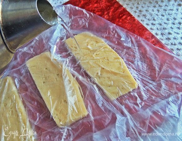 Прямо на ломтики плеснуть горячей воды из чайника. Это нужно для того, чтобы сыр стал эластичным и свернулся в рулет.