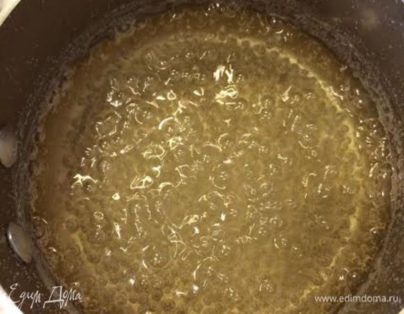 Духовку нагреть до 160°С. Нам понадобится неразъемная форма 20 см, форму хорошо смазать маслом. В кастрюле с толстым дном смешать сахар и воду, помешивая довести до кипения. Оставить кипеть, не размешивая 8-10 минут, пока сироп не станет менять цвет на золотисто-коричневый. После этого снять с огня и добавить сливочное масло, перемешать.