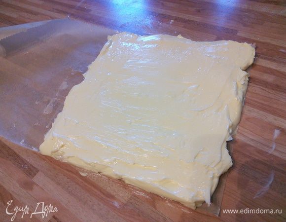 Тем временем разрезать лист пергаментной бумаги так, чтобы получить прямоугольник размером 20 x 40 cм. Сложить на половину. У нас получится квадрат размером 20 x 20 см. Бумагу раскрыть, положить внутрь масло комнатной температуры, распределить по одной стороне, накрыть другой. Масляную пластину положить также в холодильник. 