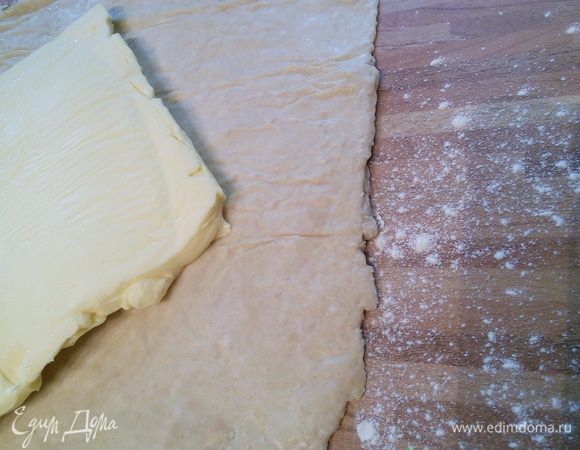 Поверхность присыпать слегка мукой, выложить тесто. Масло освободить от бумаги и выложить на пласт теста так, чтобы получить шестиконечную фигуру.  