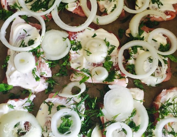 Мясо отбиваем, посыпаем солью и приправами по вкусу с двух сторон. Выкладываем на противень кусочки мяса, отступая немного друг от друга (я выкладывала на пергамент, так как его не нужно смазывать маслом и ничего не пригорает). Затем каждый кусочек смазываем майонезом, кладем нарезанную зелень и лук .