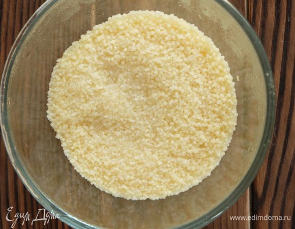 Пока баклажаны запекаются, готовим начинку. Кускус высыпаем в миску и заливаем кипятком так, чтобы вода покрывала его на 1 см. Немного солим, накрываем крышкой и оставляем на 5 минут. Затем перемешиваем вилкой, как бы взрыхляя кускус.