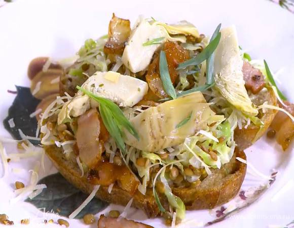 Выложить на тосты чечевицу с капустой, посыпать натертым сыром, сверху поместить кусочки сала и артишоки, украсить все листьями тархуна.