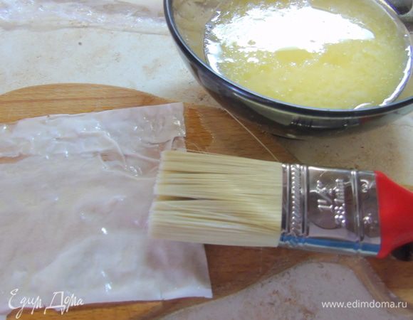 Сливочное масло растапливаем в пиале. Тесто фило нарезаем квадратами и смазываем маслом.