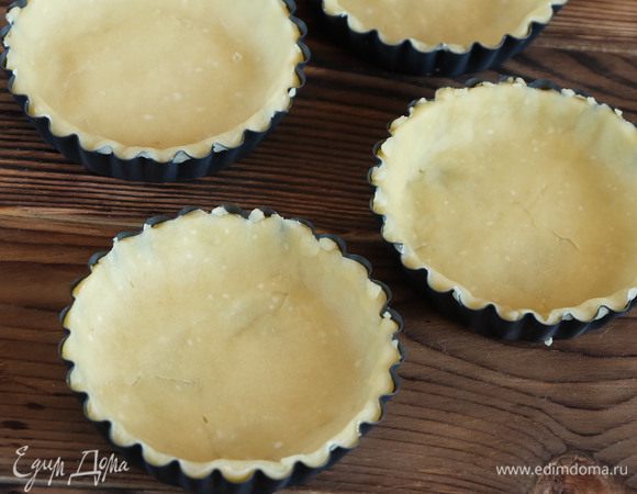 Духовку разогреваем до 180°С. Достаем пласты и вырезаем круги по диаметру больше на пару сантиметров, чем диаметр форм для тарталеток. Укладываем круги в формы, формируя бортики. У меня формочки диаметром 10 см.