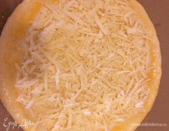 Желтки смешать с 1 ст.л молока. Края хачапури слегка загнуть, делая бортик. Середину хачапури посыпать натертым сулугуни, а края смазать желтком.