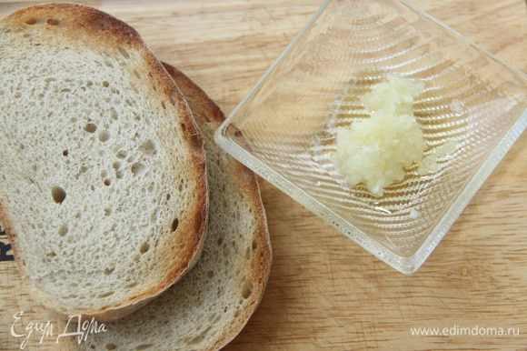 Хлеб (у меня домашний) поджарить в тостере или на гриле. Чеснок выдавить с помощью пресса и смешать с оливковым маслом. Намазать каждый кусок хлеба с обеих сторон чесночным маслом.