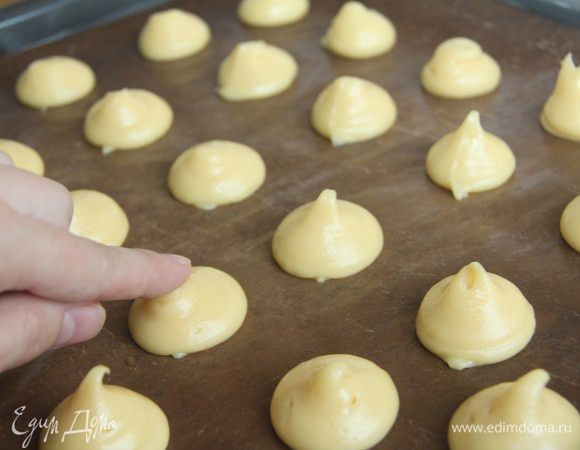 Выдавить тесто в виде шарика. Смоченным в воде пальцем придавить хвостики у будущих профитролей.